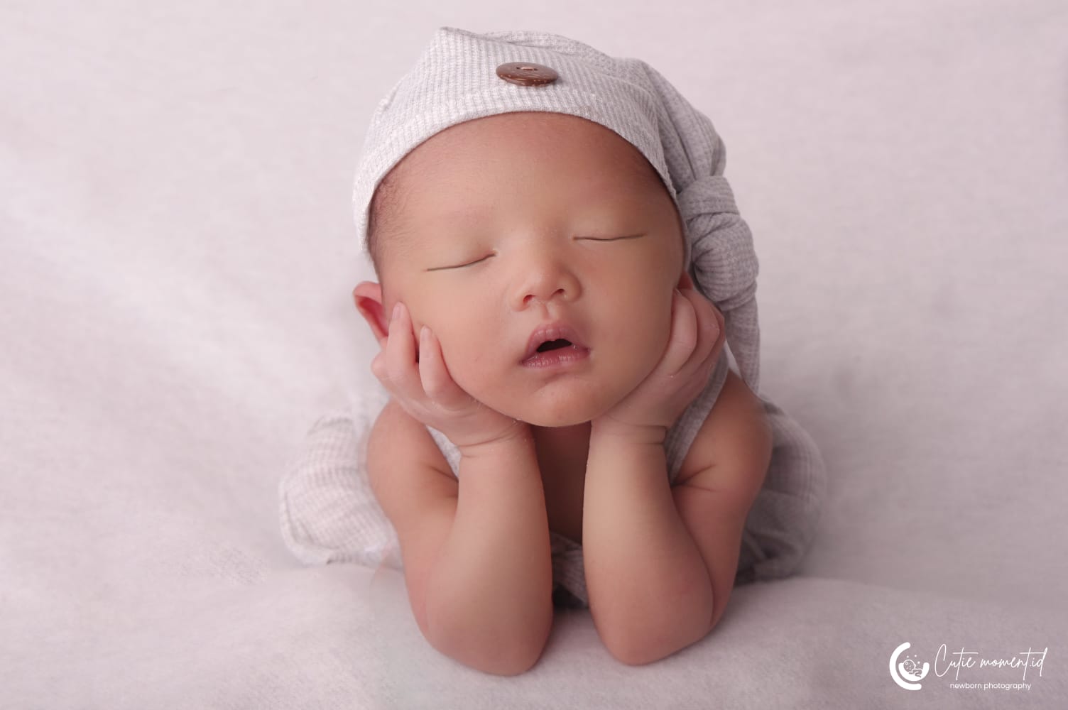 Foto close up bayi baru lahir dengan pose tangan di pipi