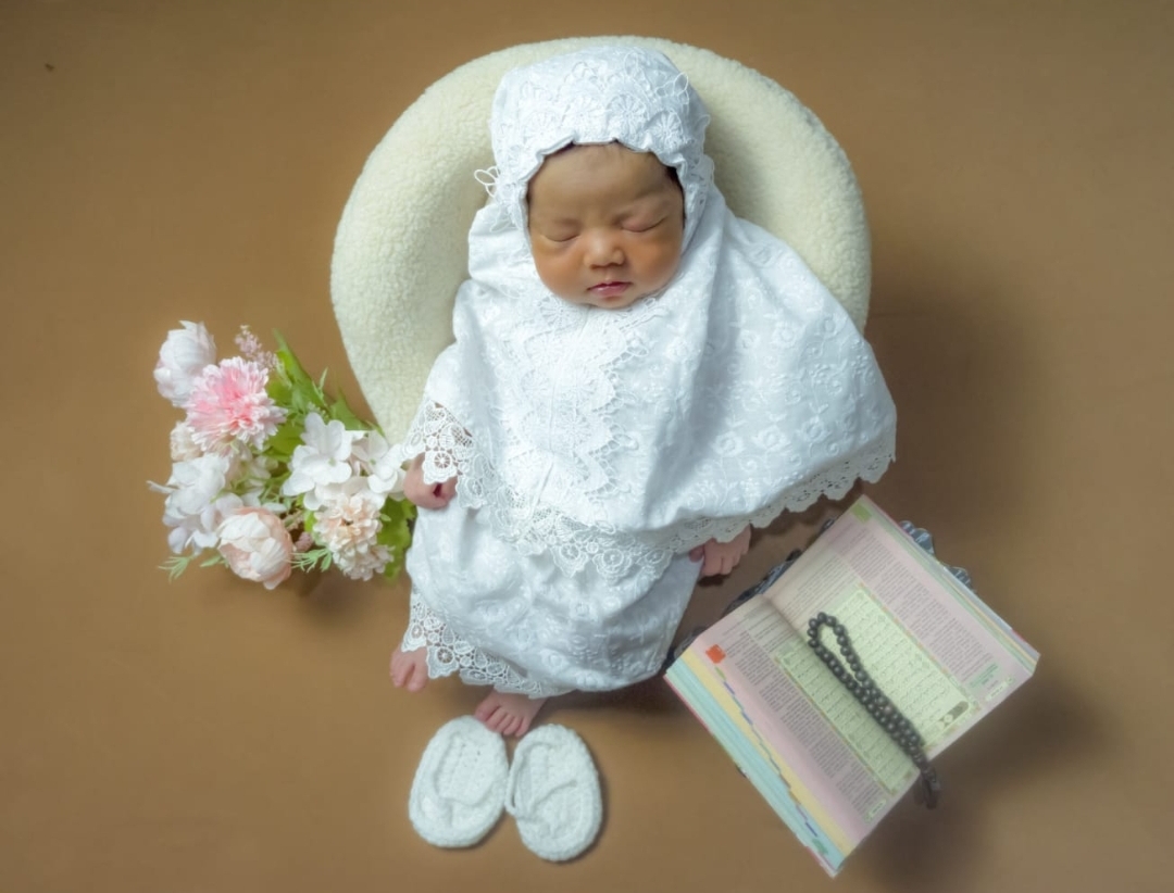 Foto bayi dengan tema islami mengenakan mukena